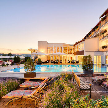 Outdoor pool with sun loungers and part of the wellness hotel.