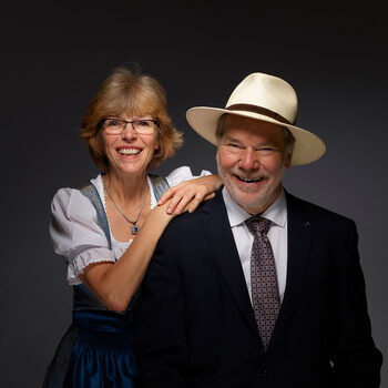 Seniorchefin Gudrun und Seniorchef Rolf Berlin lächelnd vor einem schwarzen Hintergrund.