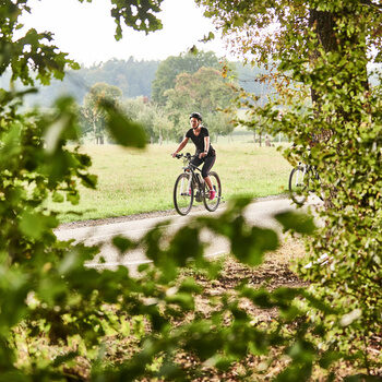 Eine junge Frau mit Fahrradhelm fährt auf einem gut ausgebauten Weg mit dem Mountainbike