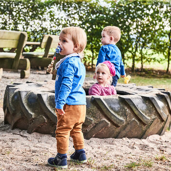 Three children play in a large hoop in the beer garden of the Zavelstein hiking home.