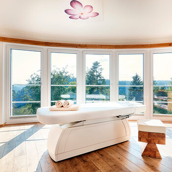 A massage table is in a spacious room with large panoramic windows.