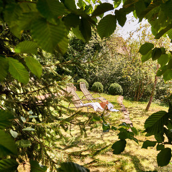 Mehrere Liegen stehen im grünen Garten des Wellnesshotels Kronelamm im Schwarzwald nebeneinander.