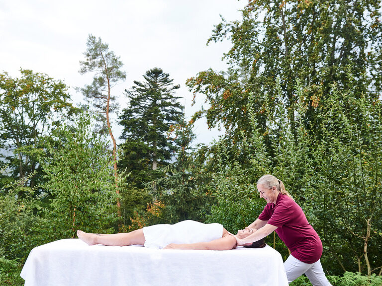 Frau auf einer Massageliege im Außenbereich des königSpa bekommt eine Massage